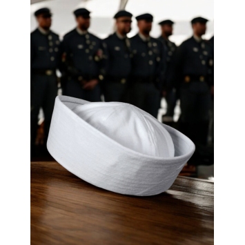 bob marin US Navy blanc posé sur table, équipage en arrière-plan flou